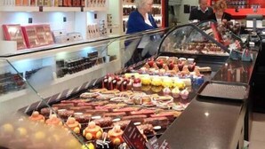 A bakery display case with various baked goods and a person in the background.