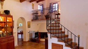 A spacious living area with a wooden staircase, a fireplace, and a wooden cabinet.