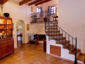 Uma sala de estar ampla com escada de madeira, lareira e um armário de madeira.