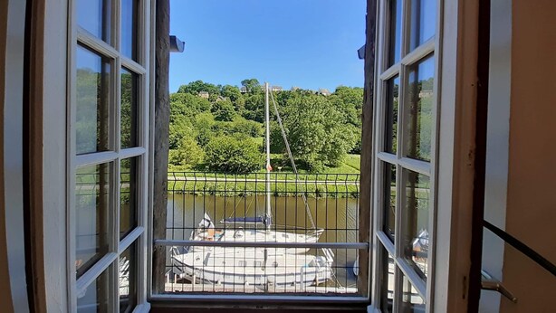 A balcony with a view of a river, boats, and a park.