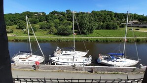 A marina with several sailboats docked, surrounded by lush greenery and a clear blue sky.