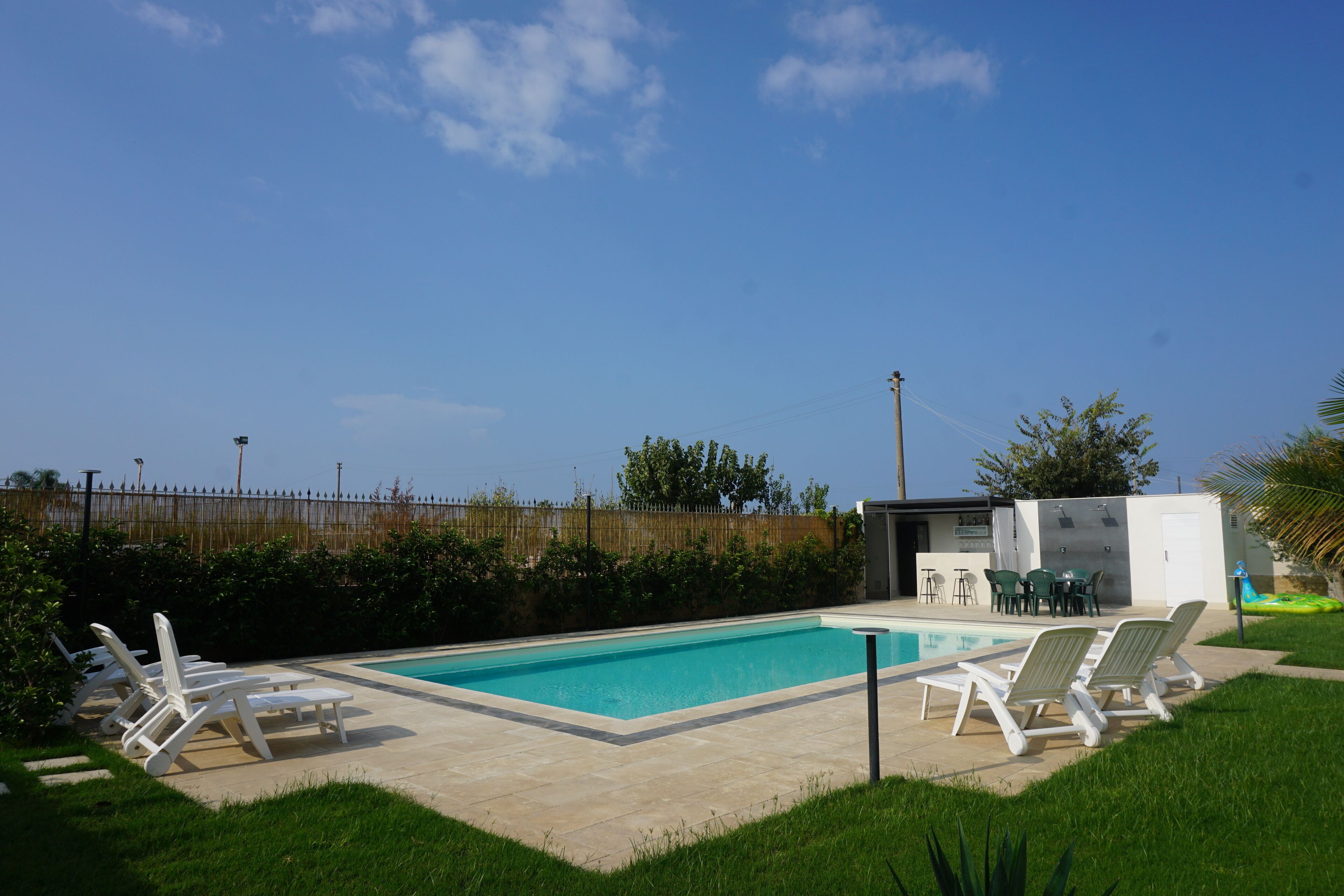 Piscina com espreguiçadeiras e um pequeno espaço de estar ao ar livre.