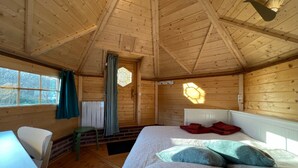 Une pièce de cabane en bois comprenant un lit, une table et une chaise.