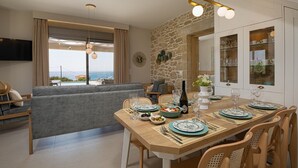 A modern dining area with a stone accent wall, a view of the sea, and a cozy seating arrangement. - New Villa★Prive Pool★Walk to all & Falasarna beach★FREE Daily Breakfast (Falasarna Crete)
