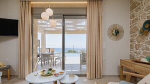 A modern hotel room with a balcony, a dining area with a table set for two, and a stone wall with decorative plates. - New Villa★Prive Pool★Walk to all & Falasarna beach★FREE Daily Breakfast (Falasarna Crete)