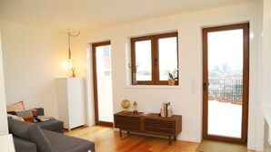 Ein modernes Wohnzimmer mit einer Couch, einer Kommode und einem großen Fenster mit Blick auf eine Stadtlandschaft.