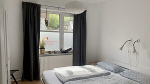 Ein Schlafzimmer mit einem Bett, Vorhängen, einem Fenster mit Blick und einer Pendelleuchte.