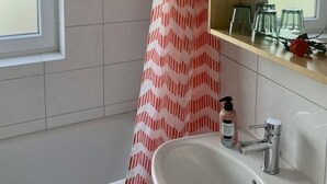 Ein Badezimmer mit einem weißen Waschbecken, einem Spiegel darüber und einem Duschvorhang mit Zickzackmuster.