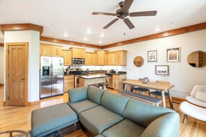 A modern kitchen with wooden cabinets, a stainless steel refrigerator, and a ceiling fan.