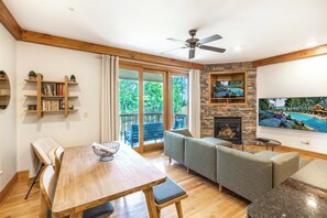 A living room with a fireplace, a television, a dining table, and a sofa.