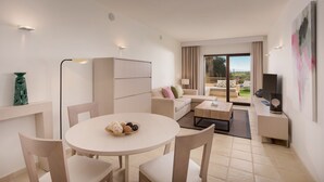 Un salon moderne avec une table ronde, un canapé beige et un téléviseur posé sur un meuble.