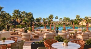Un espace de détente sur le toit, avec des sièges en plein air, une piscine et des palmiers.