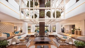 Un hall d’entrée spacieux, doté d’une table basse centrale, d’un coin salon et d’un plafond décoratif agrémenté de plantes suspendues.