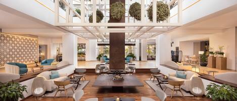 Un hall d’entrée spacieux, doté d’une table basse centrale, d’un coin salon et d’un plafond décoratif agrémenté de plantes suspendues.