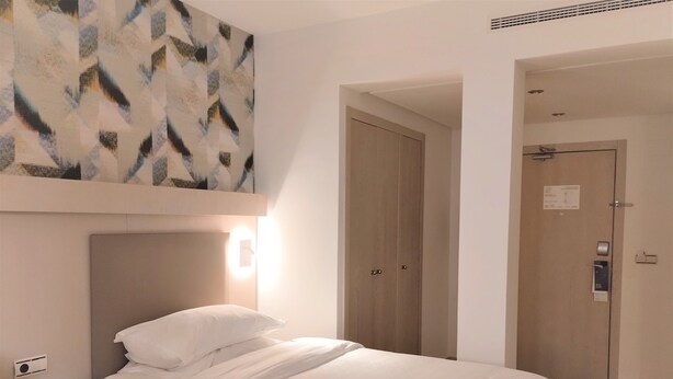 Ein Hotelzimmer mit Bett, Nachttisch und Wandleuchte.