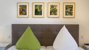 Habitación de hotel con una cama grande, dos almohadas, cabecera y cuatro cuadros enmarcados en la pared.
