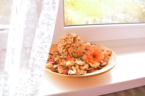 Un plato con flores secas y una esfera decorativa en un alféizar.