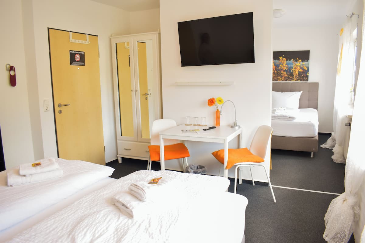 A hotel room with two beds, a desk, a TV, and a painting on the wall.