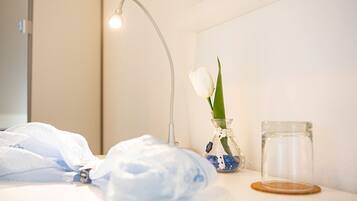 A bathroom with a white sink, a glass vase with a single white tulip, and a clear glass jar.