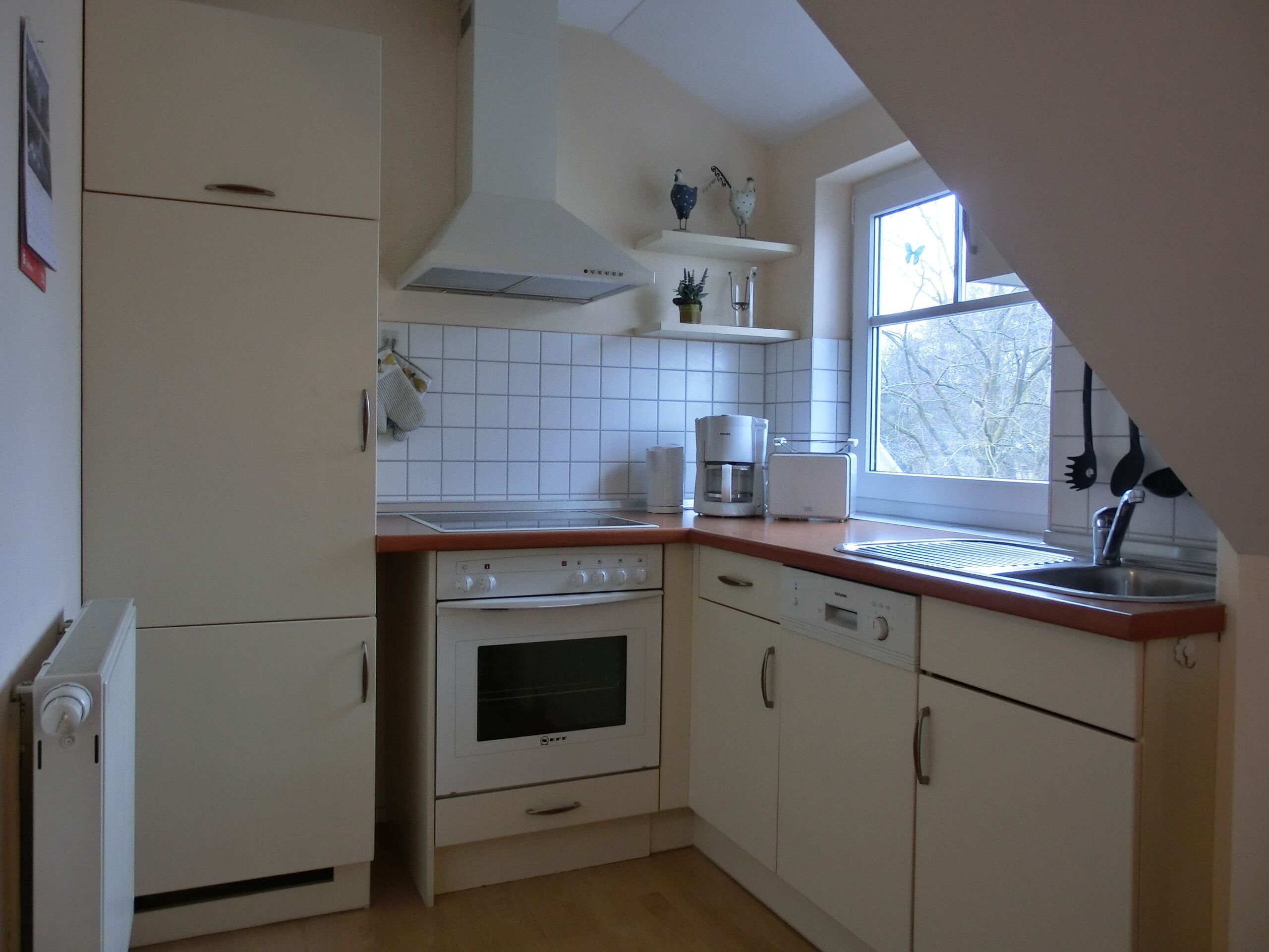 A kitchen with white cabinets, a stove, oven, and a coffee maker.