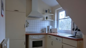 Une cuisine avec des meubles blancs, une cuisinière, un four et une machine à café.