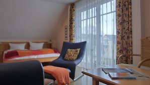 Une chambre d’hôtel avec un lit, une chaise, une table et une fenêtre avec des rideaux.
