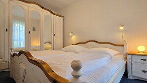 A bedroom with a large bed, a wardrobe, a bedside table with a lamp, and a nightstand. - 2-zi-ferwo für 3 Pers im EG. Wlan (Graal-Müritz)