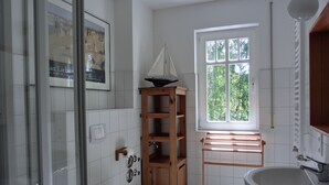 Une salle de bain avec des toilettes, une étagère en bois, une fenêtre et un lavabo.