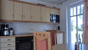 Keittiössä on puukehikoiset kaapit, mikroaaltouuni, liesi sekä ruokapöytä tuoleineen.