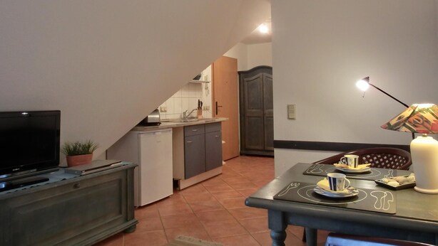 A compact living space with a kitchenette, a dining area, and a television.
