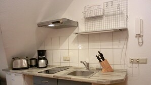 A compact kitchen with a toaster, coffee maker, and a knife block on the counter.