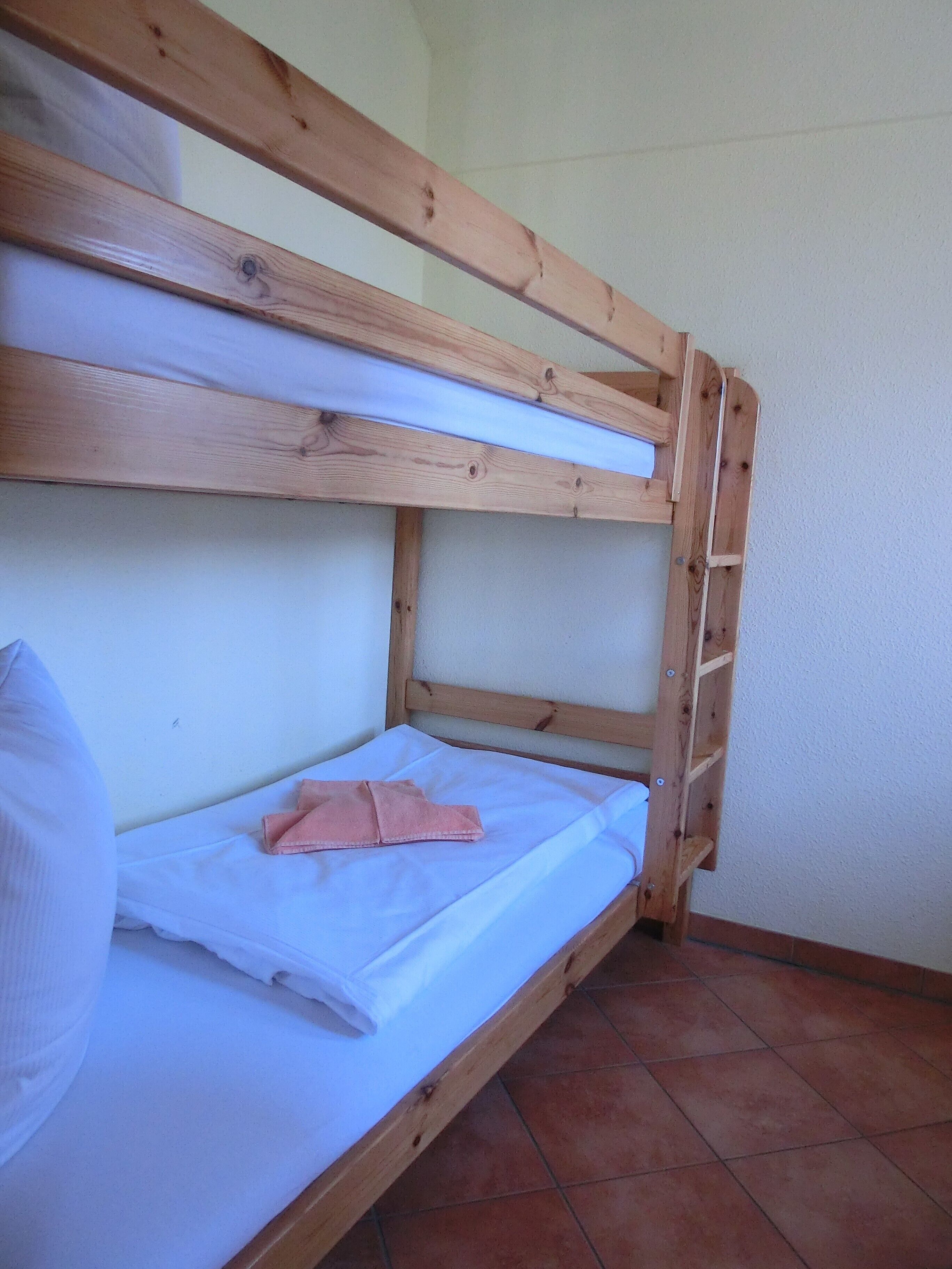 Een stapelbed met wit beddengoed en een roze handdoek.