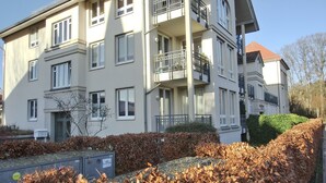 Un edificio residencial de varios pisos con balcones, buzón y seto.