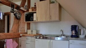 Una cocina con armarios de madera, microondas, tostadora, cafetera y lavavajillas.