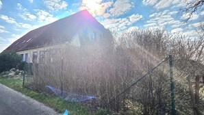 Una casa de techo inclinado, rodeada de césped y árboles.