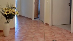 A hallway with a tiled floor, a vase of sunflowers, and a door leading to another room. - 3-room apartment close to the beach for up to 6 people with elevator (Graal-Müritz)