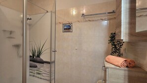 Une salle de bain moderne avec une porte de douche en verre, un porte-serviettes et une petite mosaïque décorative.