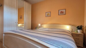 Une chambre à coucher avec un lit, une table de chevet, une lampe et un miroir.