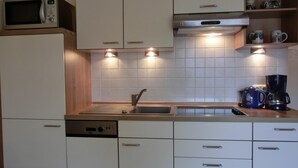 Une cuisine moderne avec des meubles blancs, un four à micro-ondes, une machine à café et un évier.