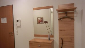 A room with a wooden wardrobe, a mirror, a small cabinet, and a door with a sign. - Strandnahe 2- Zi.-fewo für 3 Personen im 2. OG, mit Wlan (Graal-Müritz)
