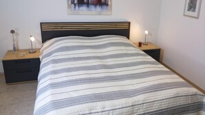 A bedroom with a bed, two bedside tables, a nightstand, a framed cityscape picture, and a small framed picture on the wall. - Strandnahe 2- Zi.-fewo für 3 Personen im 2. OG, mit Wlan (Graal-Müritz)