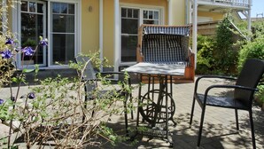 Un bâtiment jaune doté d’un balcon et d’un patio aménagé avec des meubles en osier et une table.