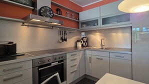 Une cuisine moderne dotée d’appareils électroménagers en acier inoxydable, de meubles blancs et d’un four encastré.