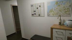 Een gang met een houten bankje, een klein kastje en een kaart aan de muur.