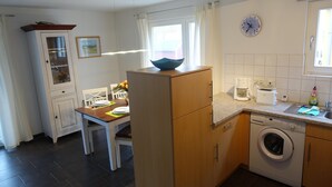 Een kleine keuken met een wasmachine, een koffiezetapparaat en een spoelbak.
