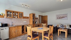 Une cuisine avec des meubles de rangement en bois, une table à manger et un canapé.