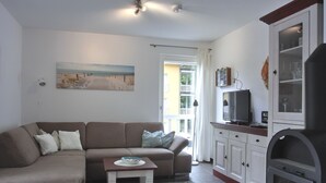 Een woonkamer met een bank, een kleine tafel, een televisie en een kast.