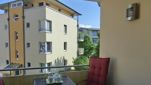 A balcony with a table set for two, chairs, and a view of adjacent buildings. - 3-zimmer-fewo im 1. OG mit Balkon mit 2 Schlafzimmern für 4 Personen, Wlan (Graal-Müritz)