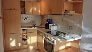 Una cocina compacta con armarios de madera, horno empotrado, pileta y cafetera.