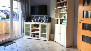 Ein Wohnzimmer mit Fernseher, Bücherregalen und einer Schiebetür zum Patio.